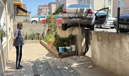 Çorlu'da el freni çekilmediği öne sürülen otomobil geri hareket ederek apartmanın istinat duvarında asılı kaldı.